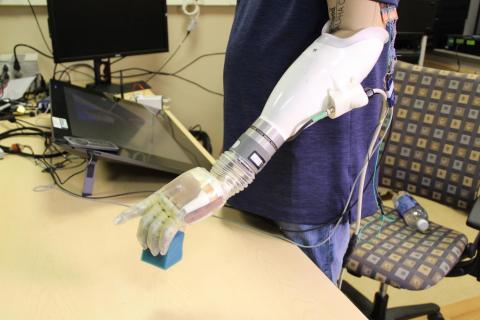 A human subject lifts a block using a feeling prosthetic. Photo: CU Boulder