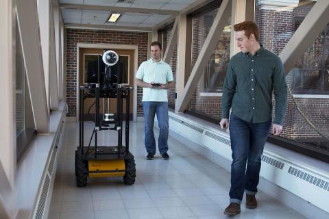 Researchers Jared Johansen (left) and Thomas Ilyevsky (right) assess the autonomous robot, Hosh, reviewing the operating systems in the environment. Photo: Hope Sale / Purdue Research Foundation image